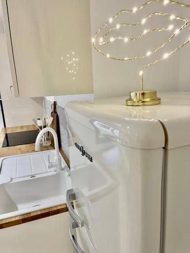 une cuisine blanche avec un évier et une lumière en forme de cœur sur un meuble dans l'établissement Rive Droite et Gauche, à Avignon