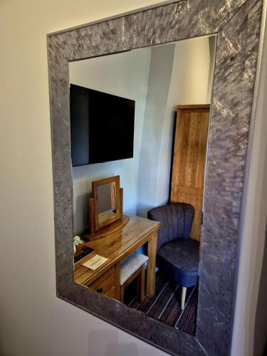 a mirror reflecting a room with a desk and a chair at The Badger Inn in Church Minshull