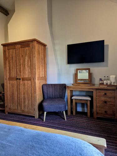 a bedroom with a tv and a chair and a desk at The Badger Inn in Church Minshull