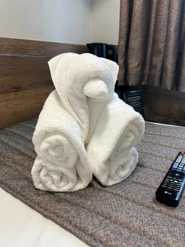a pile of towels on a bed next to a remote control at Tudor Court Hotel in London