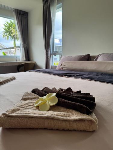 a towel on a bed with a flower on it at Modern Apartment with Queen Bed in Living Room & Separate Bedroom in Lamai