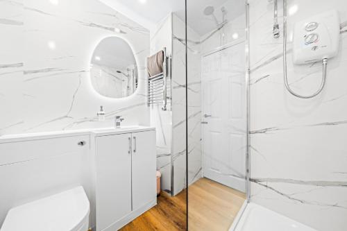 a white bathroom with a shower and a mirror at Stylish Central Glasgow Flat Near Merchant City in Glasgow
