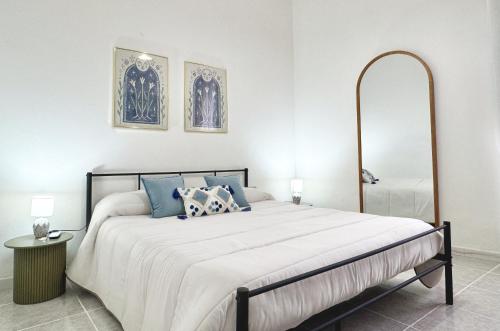 a white bedroom with a large bed with blue pillows at Casa Lia - Independent apartment in the Gulf of Orosei in Galtellì
