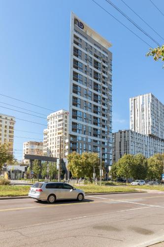 a car driving down a street with a tall building at 77 views apartments by INSHI in Lviv