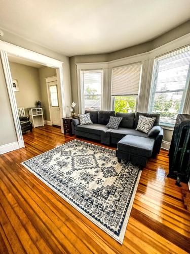 a living room with a black couch and a rug at The Red House Albany NY 4 Bedroom Private Apartment in Albany