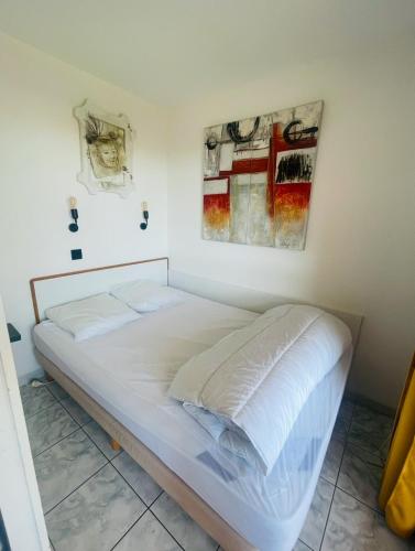 - un lit blanc dans une chambre ornée d'une peinture murale dans l'établissement Lake view apartment with pool, au Barcarès