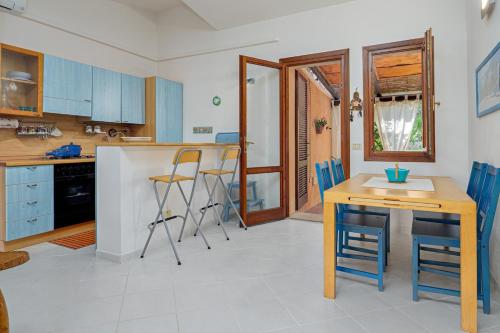a kitchen with blue cabinets and a table and chairs at Casa del Leccio - Sea View 5 Minutes from Palau in Palau