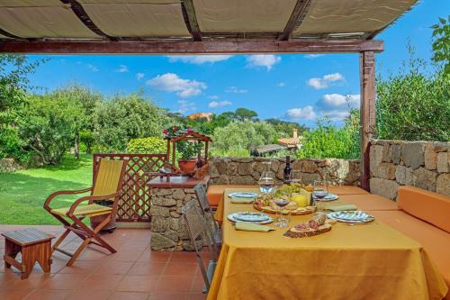 a table with a yellow table cloth on a patio at Casa del Leccio - Sea View 5 Minutes from Palau in Palau