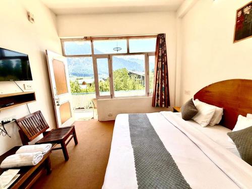 a bedroom with a large bed and a large window at Hotel The Premium Villa Old Manali View in Manāli