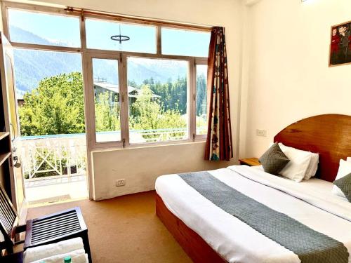 a bedroom with a bed and a large window at Hotel The Premium Villa Old Manali View in Manāli