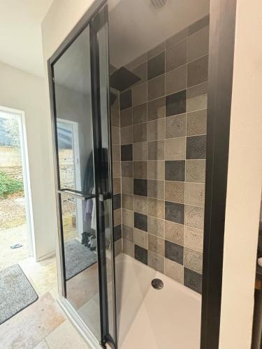 une douche avec une porte vitrée dans une salle de bain dans l'établissement Studio avec accès piscine, à Nîmes