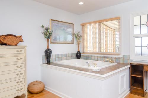 a white bathroom with a tub and a window at Carolina Joy by Bryant Real Estate in Carolina Beach