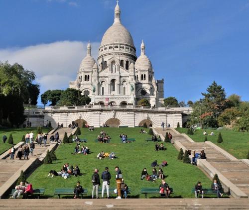personnes assises sur l'herbe devant un bâtiment dans l'établissement Charmant studio au pied de Montmartre dans résidence avec gardien et caméra de surveillance, à Paris