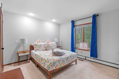 a bedroom with a bed with blue curtains and a window at Spacious Game Room Seclusion Hot Tub and more in Long Pond