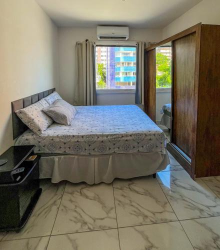 a bedroom with a bed and a window at Flat Jardim Aeroporto - H in Lauro de Freitas