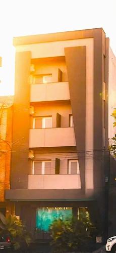 a tall white building with a green sign in front of it at LG Golden Suites in San Miguel de Tucumán