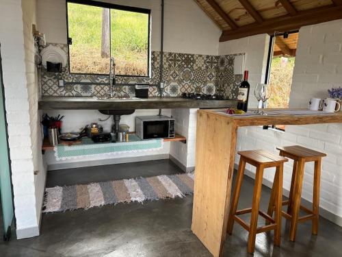 a kitchen with a sink and a counter with stools at Belo Nascer 2 in Joanópolis
