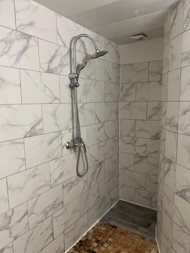 La salle de bains est pourvue d'une douche et de carrelage en marbre blanc. dans l'établissement Le Montclair Montmartre by River, à Paris