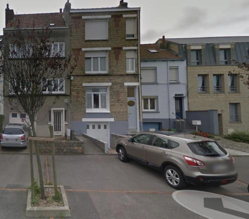 a car parked in a parking lot in front of buildings at Souplex Laverie Jardin Parking Villa Margareth in Dunkerque