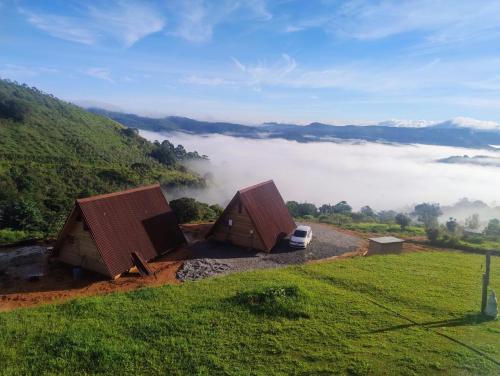 two small huts on a hill with a car in a field at Montanha Home in Monte Verde