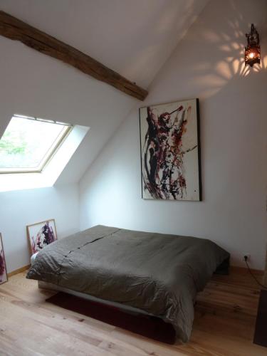 une chambre avec un lit dans une pièce avec une fenêtre dans l'établissement L'escalier des rêves gîte, à Saint-Sauveur-en-Puisaye