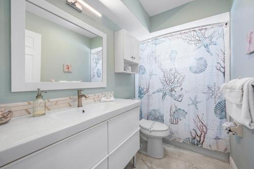a bathroom with a toilet and a shower curtain at Hidden Treasure Unit A! Modern duplex with shared pool just 200 steps to the beach! in Bradenton Beach