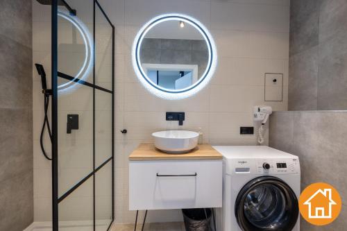 a bathroom with a washing machine and a mirror at Apartamenty ApartPark - visitopl in Świnoujście