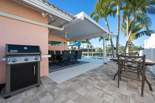 a patio with a grill and a table and chairs at Whispering Palms! Private canal side dock and pool with spa! in Bradenton