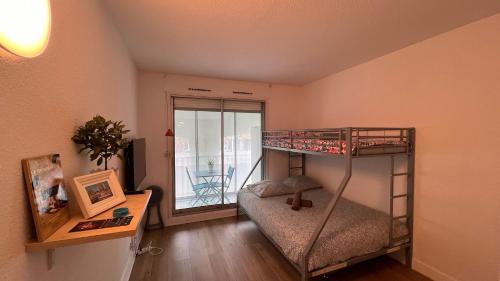 Cette petite chambre comprend des lits superposés et un bureau. dans l'établissement La Cachette 44, à La Grande Motte