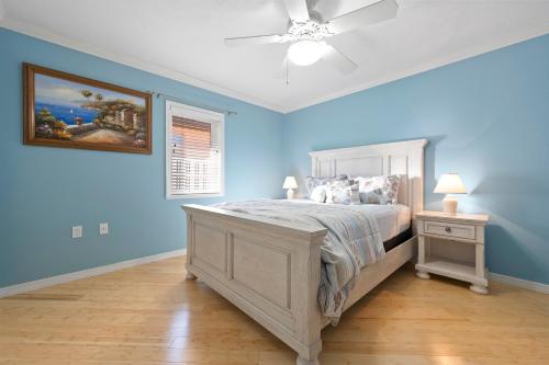 a blue bedroom with a bed and a ceiling fan at Whispering Palms! Private canal side dock and pool with spa! in Bradenton