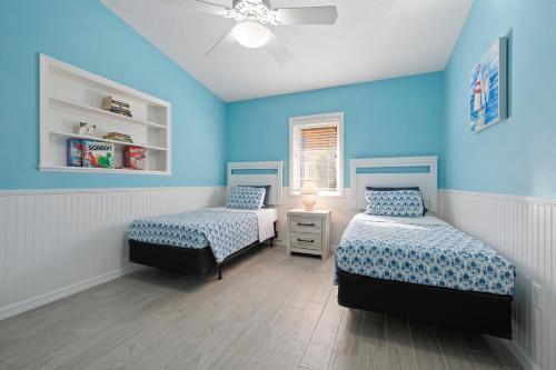 two beds in a room with blue walls at Whispering Palms! Private canal side dock and pool with spa! in Bradenton
