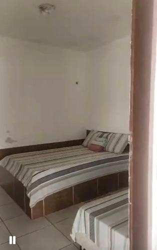 a bed in a room with a white wall at Suites&Flats Galinhos in Galinhos