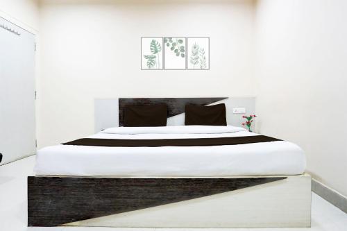 a white bedroom with a large bed with black pillows at SPOT ON Hotel Swarat in Satna