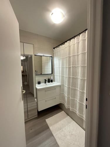 une salle de bain blanche avec un lavabo et un miroir dans l'établissement Chic Parisian Sacre Coeur views, à Paris