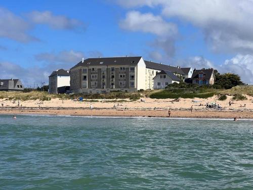 ein Gebäude am Strand neben einem Strand in der Unterkunft La Marinière, appartement avec garage, 2 étoiles à 100m de la mer in Barneville-Carteret