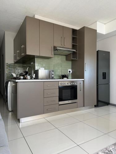 a kitchen with stainless steel appliances and gray cabinets at Haven at Merensky in Windhoek