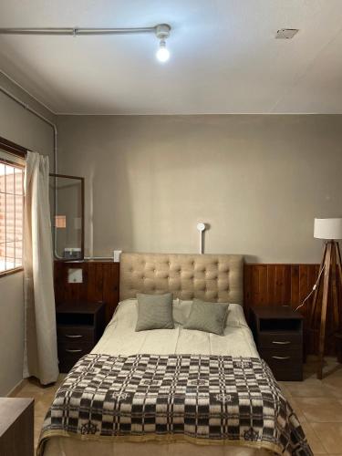 a bedroom with a large bed with a checkered blanket at La moora in Alta Gracia