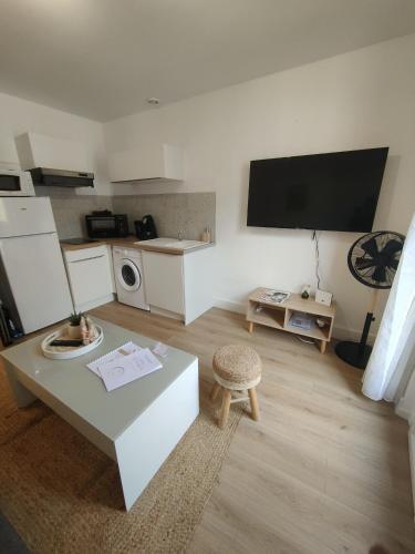 un salon avec une table et une télévision au mur dans l'établissement Le petit coin périgourdin, à Bergerac