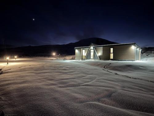 a building in the middle of a snowy road at night at Ledgowan Bunkhouse in Achnasheen