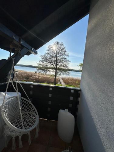a balcony with a swing and a tree and the ocean at Apartament nad jeziorem w Charzykowach in Charzykowy