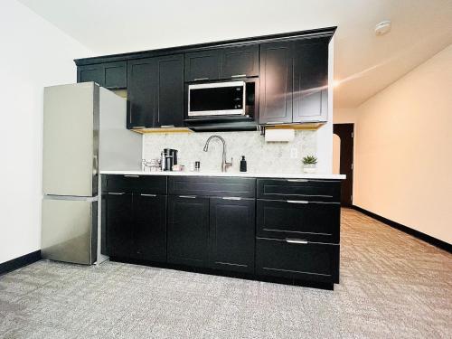 a kitchen with black cabinets and a stainless steel refrigerator at The 419 Ten-room Boutique In Sandusky in Sandusky
