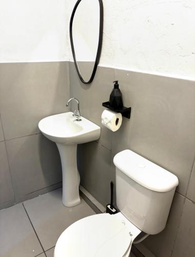 a bathroom with a toilet and a sink and a mirror at Pousada Lemon Suítes - Praia do Sesc Acesso Vista Linda e Centro in Bertioga