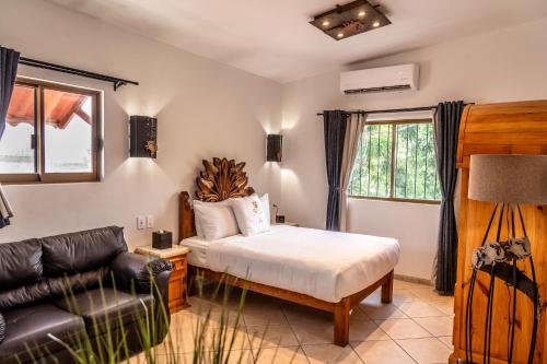 1 dormitorio con cama y sofá de cuero en 5 Frogs Hotel Bucerias, en Bucerías