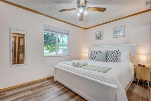 a white bedroom with a bed and a ceiling fan at Runaway Escapade! Hot Tub, BBQ & Fire Pit in Colorado Springs