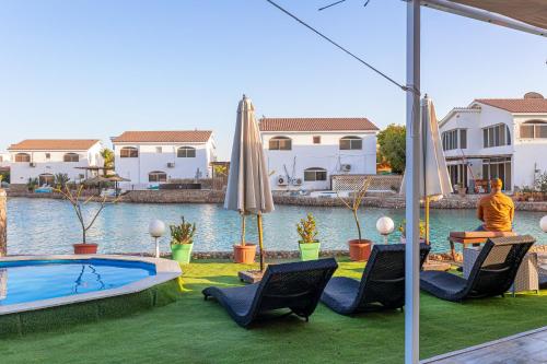 a backyard with a swimming pool and chairs and an umbrella at Aden Beach - Sea View room with beach access in Villa in Hurghada