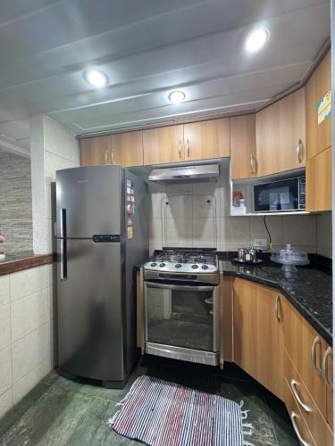 a kitchen with a stainless steel refrigerator and wooden cabinets at Le Corsaire, 38 in Búzios