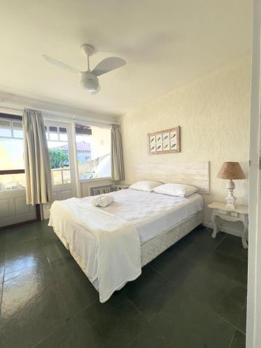 a bedroom with a large white bed with a ceiling fan at Le Corsaire, 38 in Búzios