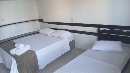 a bedroom with two beds with white sheets and towels at Hospedagem Clima Mar in Valença
