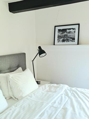 a bedroom with a white bed and a lamp at Gårdshotellet in Ystad