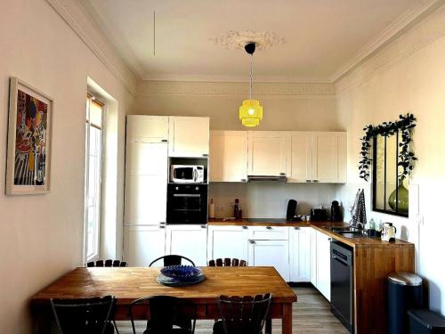 une cuisine avec une table en bois et des armoires blanches dans l'établissement Charming Flat in Nice Villa, à Nice